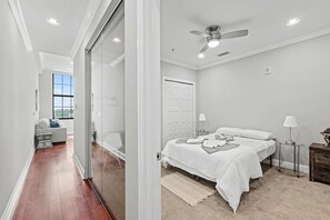 Ein Schlafzimmer mit einem Bett, Nachttischen, einem Deckenventilator und Blick ins Freie.