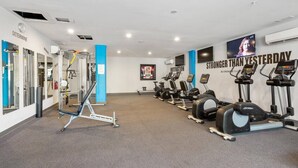 Uma academia com equipamentos de cardio, aparelhos de musculação e cartazes motivacionais.