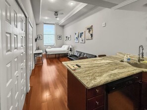 A hotel room with a bed, a desk, a chair, a dining table, and a kitchen area. - Sleek Studio near The Fillmore | NoLibs | Sleeps 2 (Philadelphia)