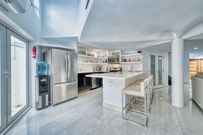 A modern kitchen with a central island, stainless steel appliances, and built-in shelving.