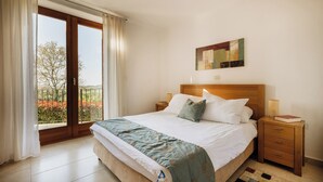 A bedroom with a large bed, a nightstand, a lamp, a painting, and a view through a sliding door. - Villa Morgan – Luxury Villa with Heated Pool near Buje (Buje)