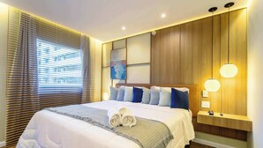 A neatly made bed with a rolled towel, a bedside table with a lamp, and a wall-mounted shelf. - #VD1226 | Cyclinn Berrini Chacara Sto Antonio (Berrini)