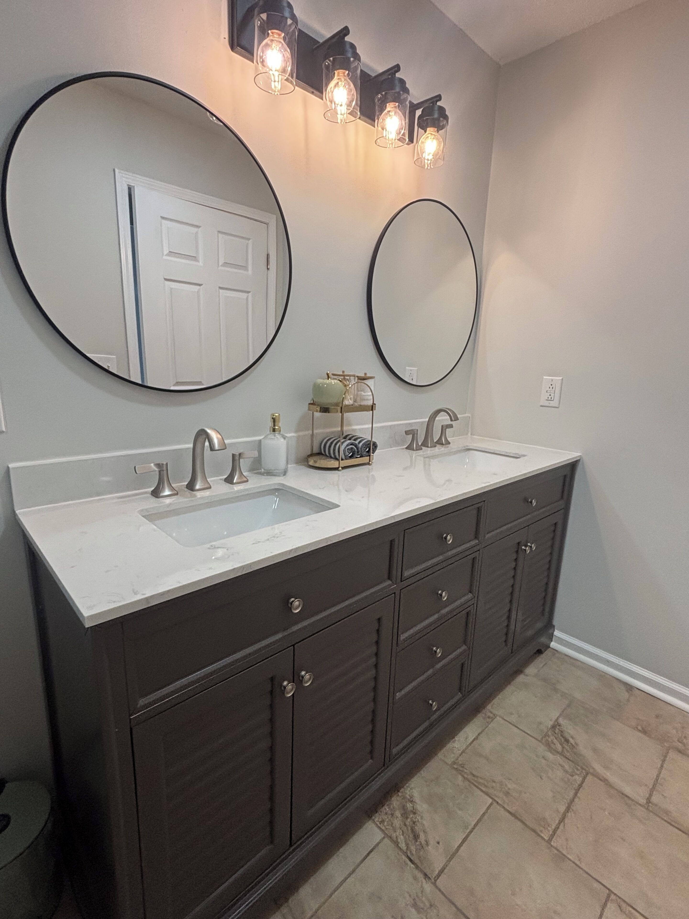 A bathroom with two sinks, dark cabinets, and two wall-mounted mirrors.