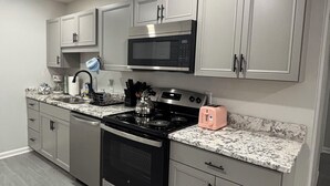 A modern kitchen with stainless steel appliances, grey cabinetry, and a marble countertop. - Delightful 2B/2B modern & Brand new centrally located (Florence)