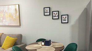 A dining area with a round table, green chairs, a yellow cushion on a grey sofa, and framed artwork on the wall. - Delightful 2B/2B modern & Brand new centrally located (Florence)
