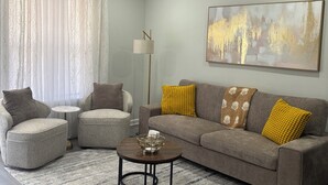 A modern living room with a ceiling fan, a sofa with cushions, a coffee table, and a floor lamp. - Delightful 2B/2B modern & Brand new centrally located (Florence)