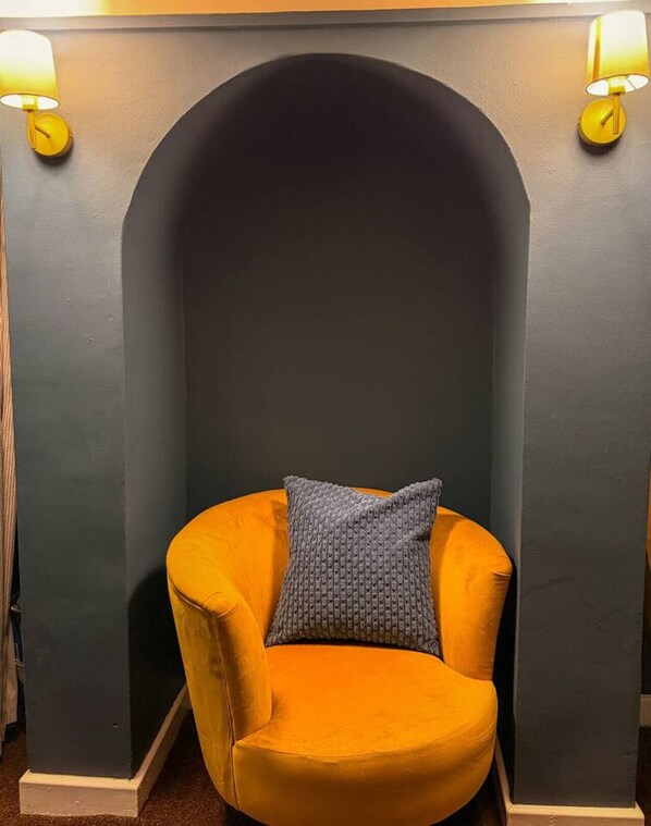 A corner with a yellow armchair, a grey knitted pillow, and two wall-mounted lamps. - Victorian 5-Bed Home| Loft |Walk to City & Cricket (Worcestershire)