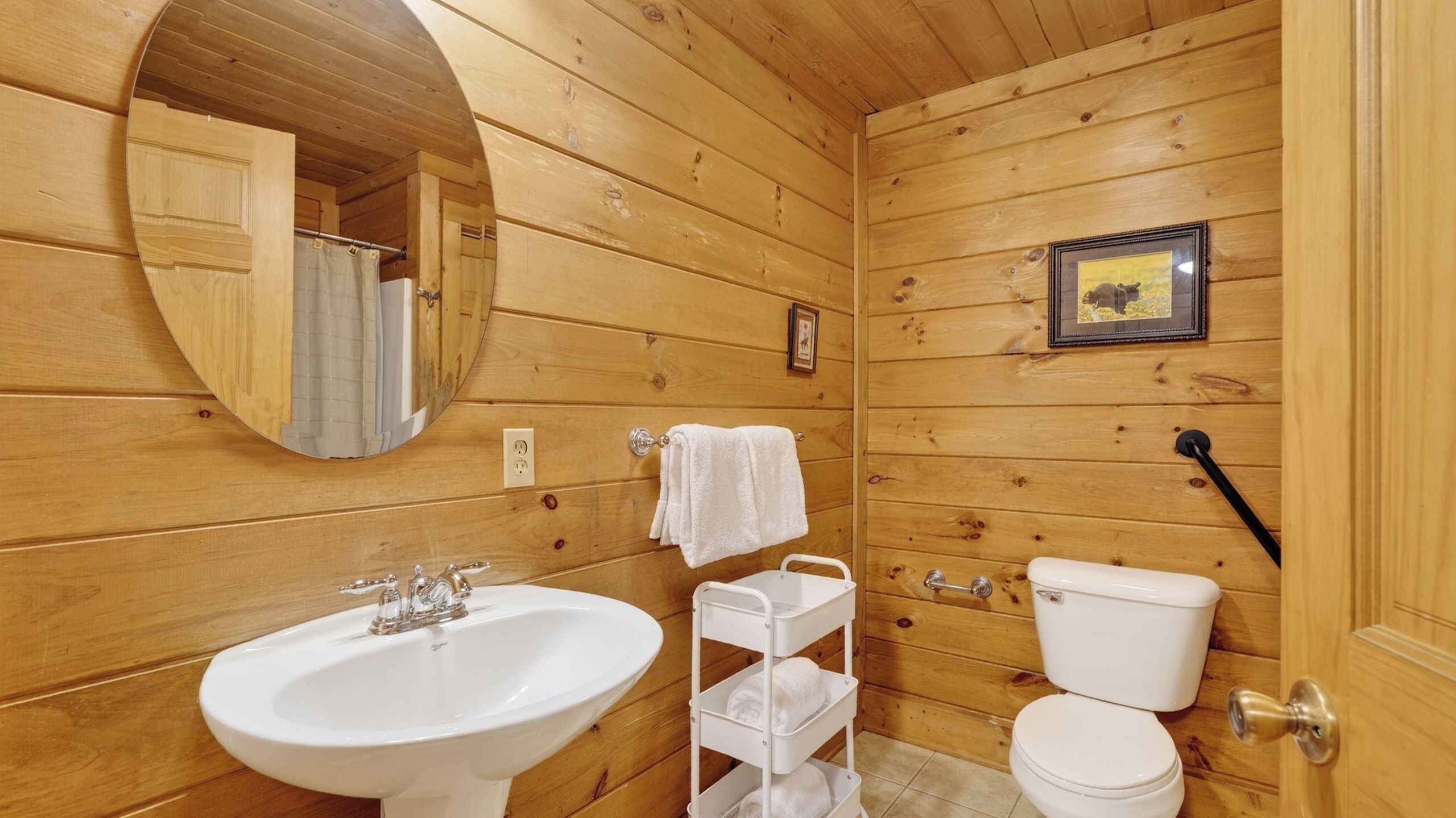 Ein Badezimmer einer Holzhütte mit Waschbecken, Toilette und Spiegel.