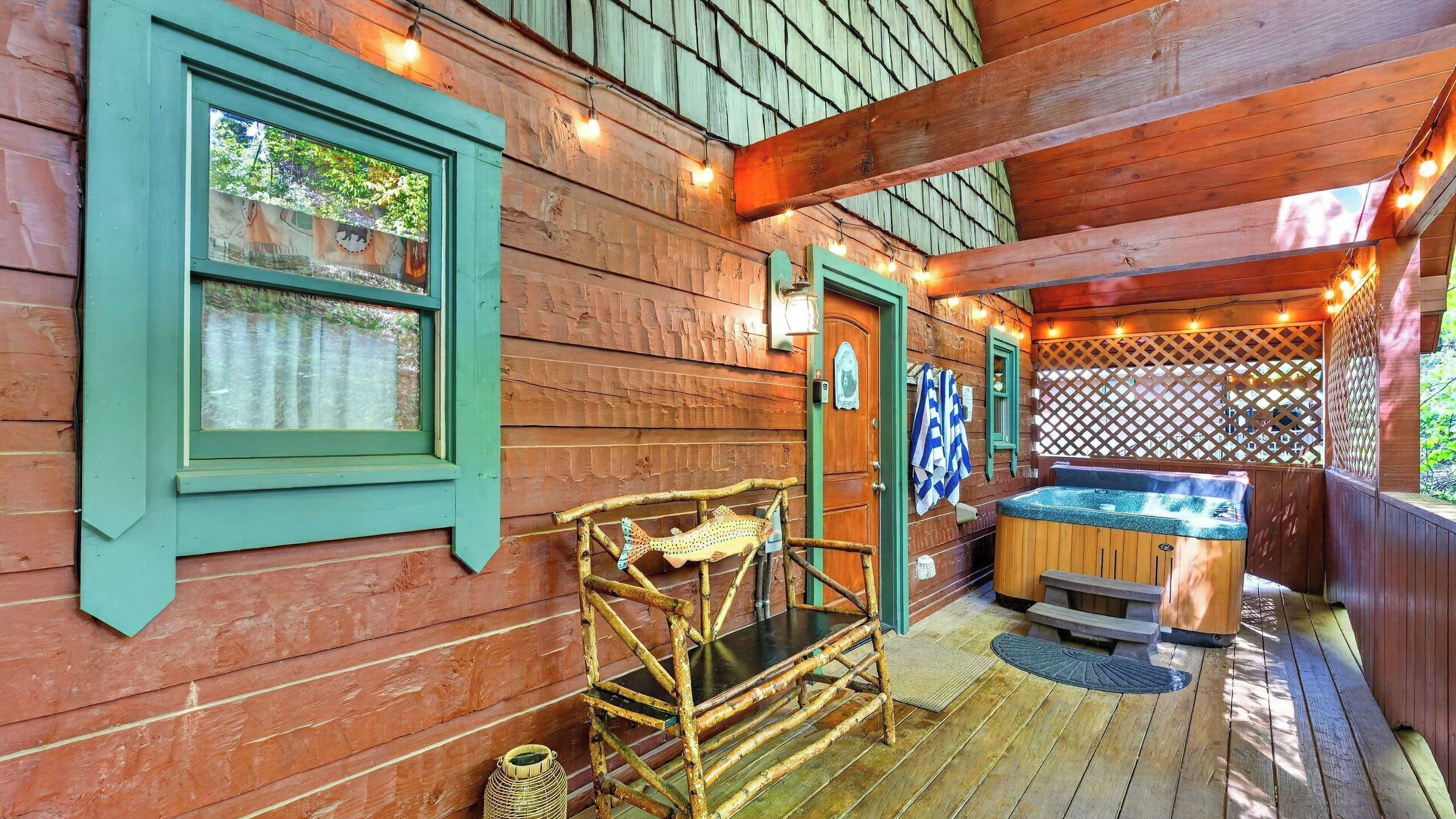 A wooden cabin with a hot tub, a wooden deck, and a bamboo chair.