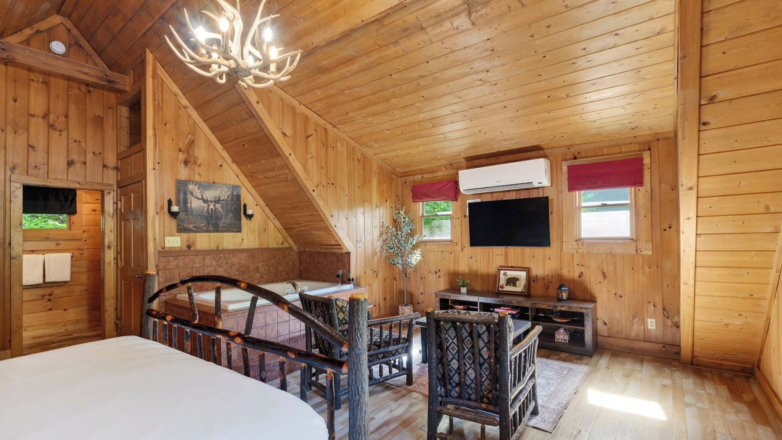 Uma cabana de madeira com quarto no mezanino, área de refeições e sala de estar com lareira.