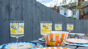 A table set with striped orange and white plates, a glass, and a bowl with a citrus pattern. - Stylish 3BR Victorian House | Garden, BBQ, Parking (Worcestershire)