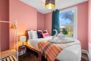 Une chambre à coucher avec un lit, une lampe de chevet, une fenêtre donnant sur un beau paysage et une serviette en forme de cygne.