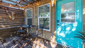 A covered patio with a teal door, a table with chairs, and a wall-mounted hookah.