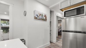 A modern kitchen with a stainless steel refrigerator, white cabinetry, and a painting on the wall.