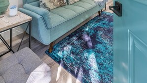 A modern living room with a teal sofa, a coffee table, and a rug.