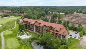 A lodge with multiple floors, a swimming pool, and a golf course in the background.