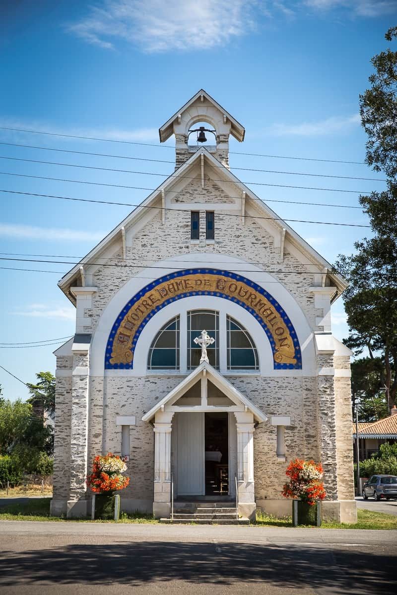 A church with a stone facade, a bell tower, and a sign reading 'Saint-Pierre de Courmelon.'