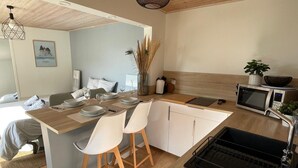 A modern kitchen with a wooden island, white chairs, a microwave, and a sink. - To complete (Pornic)