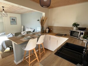 Eine moderne Küche mit einer Holzinsel, weißen Stühlen, einer Mikrowelle und einem Spülbecken.