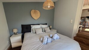 A bedroom with a bed, bedside tables, a hanging light fixture, and a wall-mounted heart decoration. - To complete (Pornic)