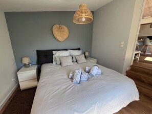 Ein Schlafzimmer mit einem Bett, Nachttischen, einer Hängeleuchte und einer Wanddekoration in Herzform.