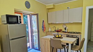 Una cocina compacta con refrigerador, microondas y un pequeño comedor con dos sillas.