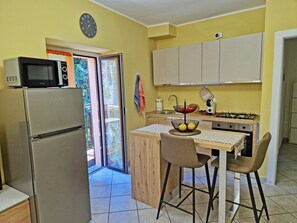 A compact kitchen with a refrigerator, microwave, and a small dining area with two chairs. - [Romantic Stay - Lake Como - 50m from the lake] (Ossuccio)