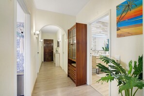 A hallway with wooden flooring, a wooden cabinet, a door, and a plant. - Apartment 'Casa Lanna Medeiros' with Shared Pool, Wi-Fi and Air Conditioning (Albufeira)