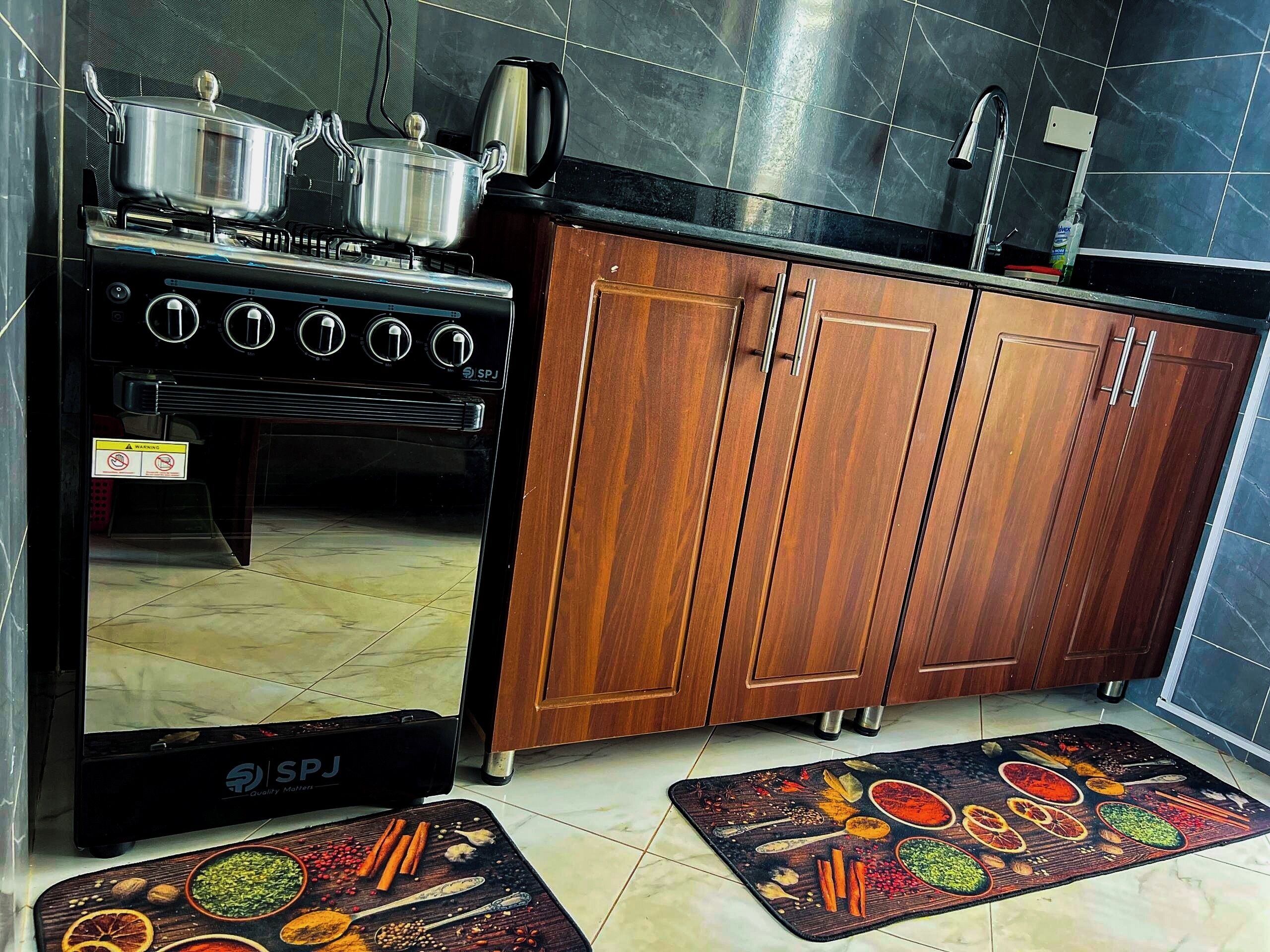Een keuken met een fornuis, kastjes en een kruidenmat op de vloer.