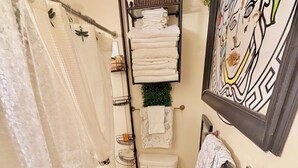 Un baño con inodoro, cortina de ducha, lavamanos, toallero y un cuadro en la pared.