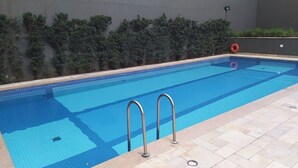 Una piscina rectangular con azulejos azules, barandillas de metal y un flotador en la pared.