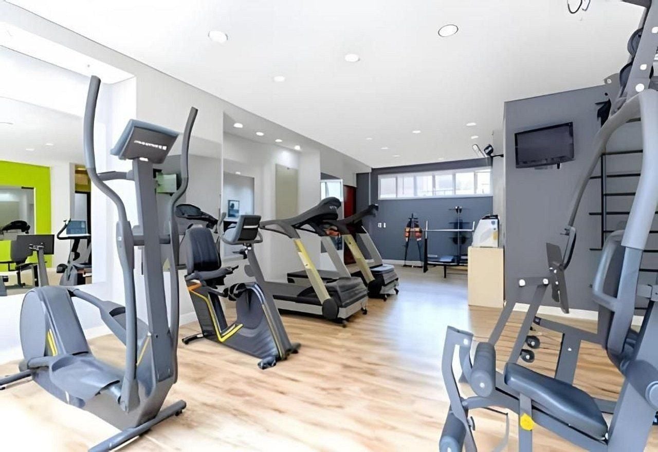 Un gimnasio con diversas máquinas de ejercicio, incluyendo cintas de correr y elípticas.