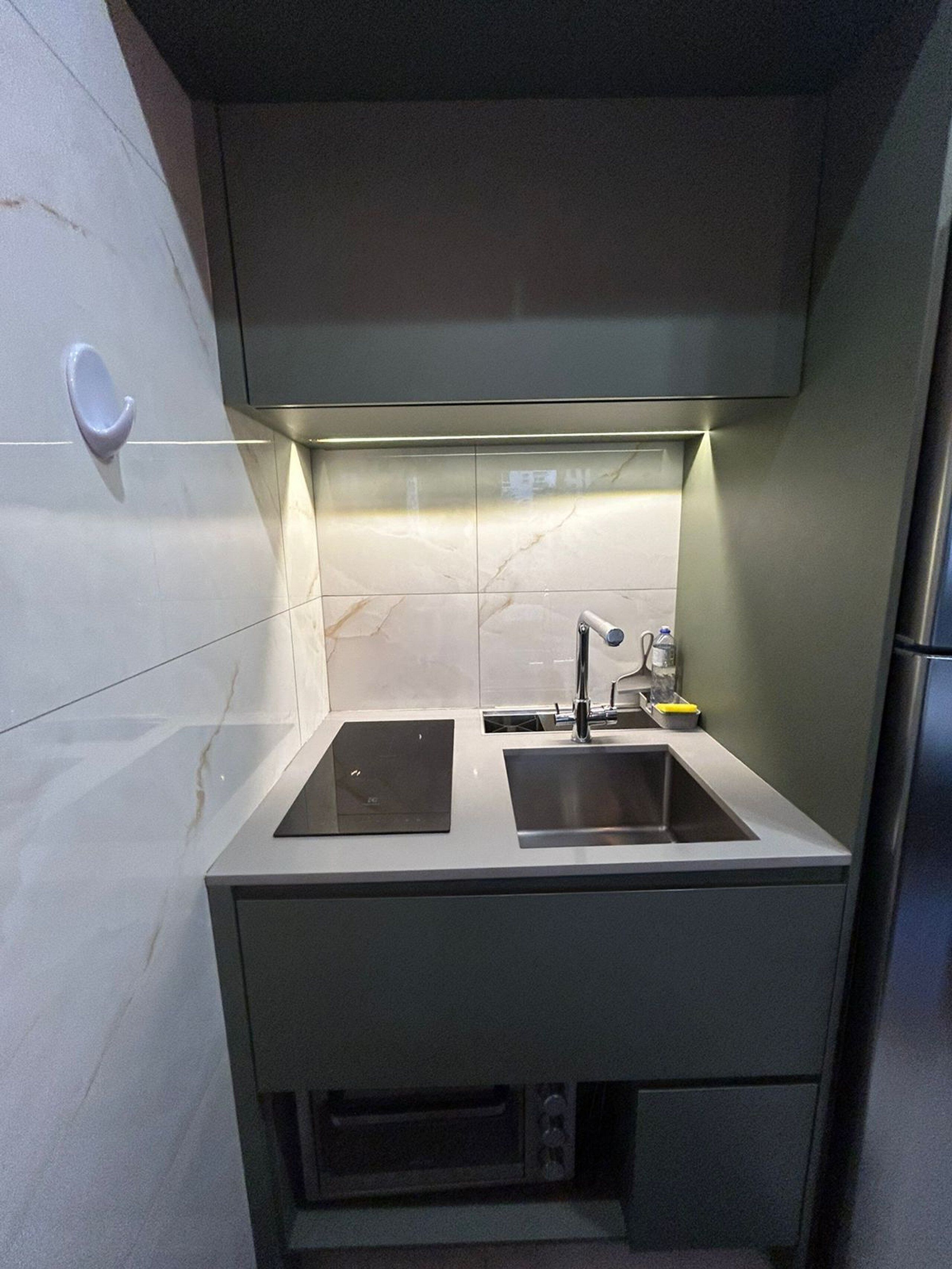 Una cocina compacta con dos fregaderos, horno empotrado y un refrigerador pequeño.