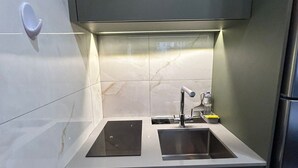 Una cocina compacta con dos fregaderos, horno empotrado y un refrigerador pequeño.