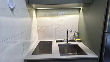 Una cocina compacta con dos fregaderos, horno empotrado y un refrigerador pequeño.