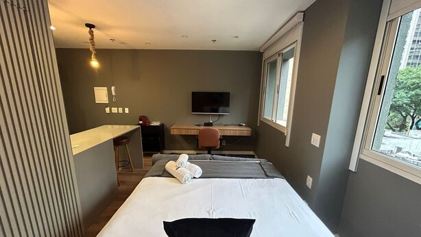 Una habitación de hotel con cama, escritorio, silla, televisión y ventana.