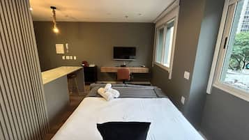 Una habitación de hotel con cama, escritorio, silla, televisión y ventana.