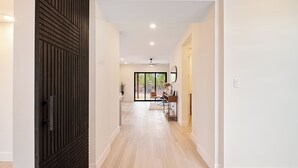 Un pasillo con una puerta de madera, un ventilador de techo y vistas a una habitación con un escritorio y una silla.