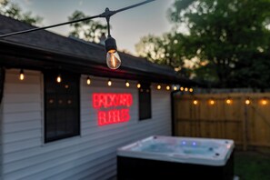 A hot tub outside a building with a neon sign reading 'BRICKY BAR'. - 5 min to Speedway; Luxury; Game Room; Hot Tub (Indianapolis)