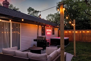 Eine Terrassenanlage im Garten mit Gartenmöbeln, einem Grill und Lichterketten.