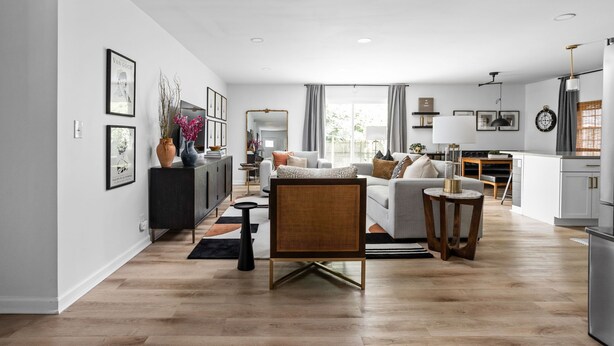 A modern living room with a sofa, coffee table, and a dining area with a table and chairs.