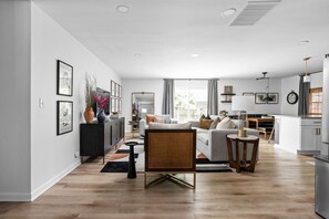 A modern living room with a sofa, coffee table, and a dining area with a table and chairs. - 5 min to Speedway; Luxury; Game Room; Hot Tub (Indianapolis)