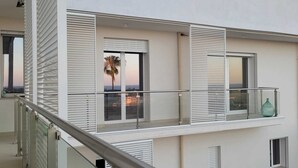 Ein modernes Gebäude mit Balkonen, großen Fenstern und Blick auf eine Palme.