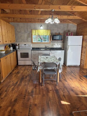 A compact kitchen with wooden cabinets, a stove, a microwave, and a refrigerator.