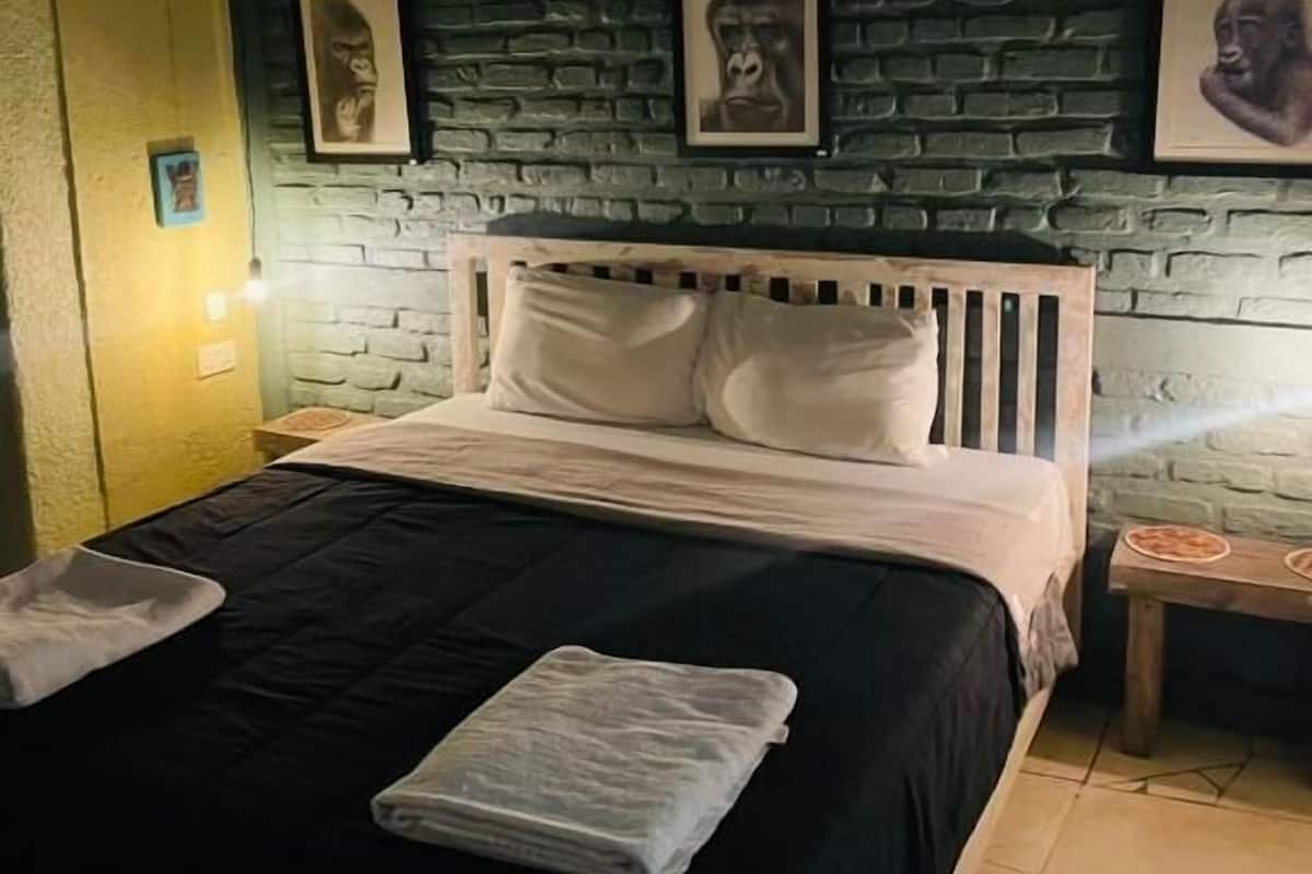 A bed with white bedding, a brick-patterned wall, and framed pictures.