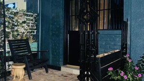 A covered outdoor area with a blue wall, a black metal structure, and a small table. - Saish Stay (Muhoza)