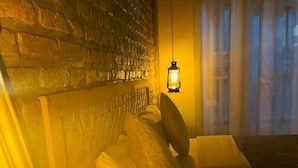 A room with a brick wall, a bed with pillows, a hanging light, and a window with a view. - Saish Stay (Muhoza)