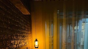 A cozy room with a brick wall, a hanging lantern, and a view through a window. - Saish Stay (Muhoza)