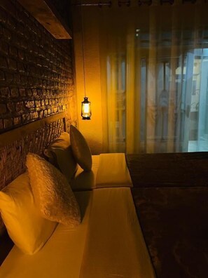 Una habitación acogedora con una pared de ladrillo, un farol colgante y vistas a través de una ventana.