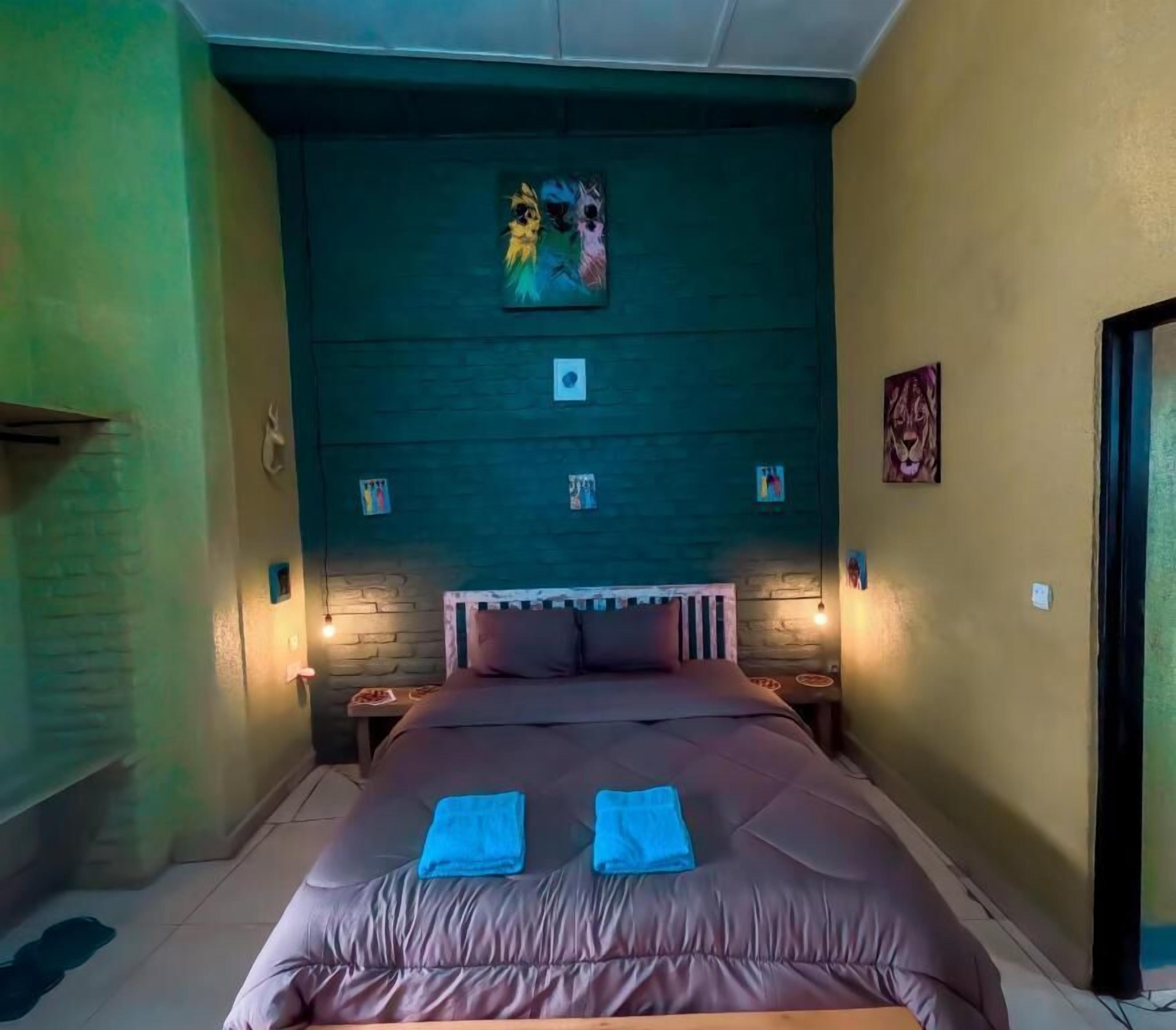 A bedroom with a large bed, a headboard with a painting, and two bedside lamps.